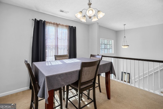 dining area with light carpet, a textured ceiling, and an inviting chandelier