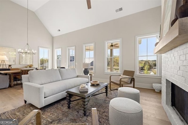 living room with plenty of natural light, a fireplace, and ceiling fan with notable chandelier