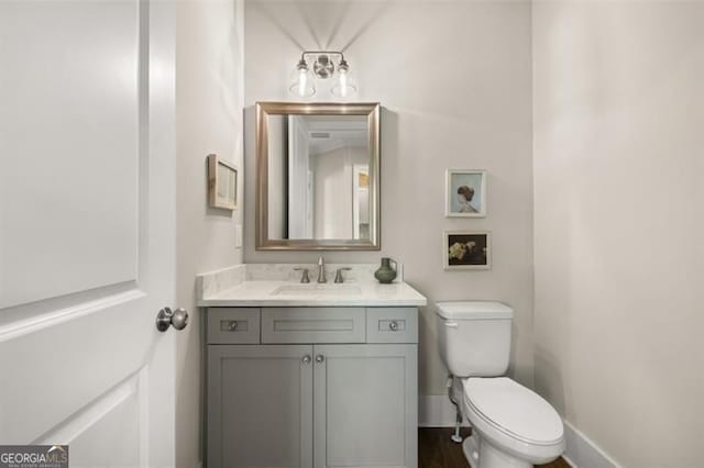 bathroom featuring toilet, baseboards, and vanity