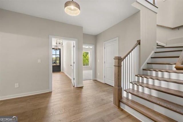 entryway featuring stairway, wood finished floors, and baseboards