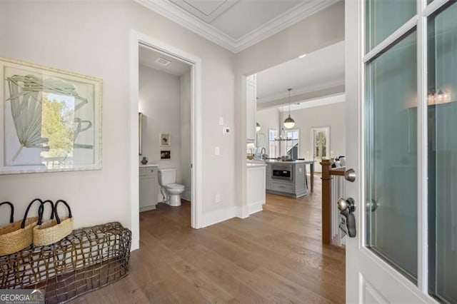 hall with ornamental molding, baseboards, and wood finished floors