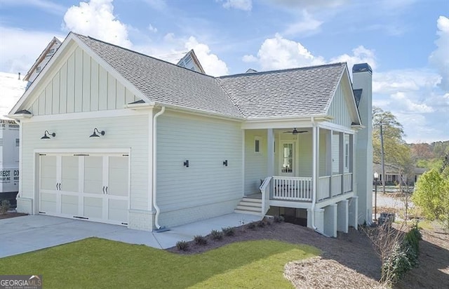 view of front of property with an attached garage, covered porch, a shingled roof, board and batten siding, and a chimney