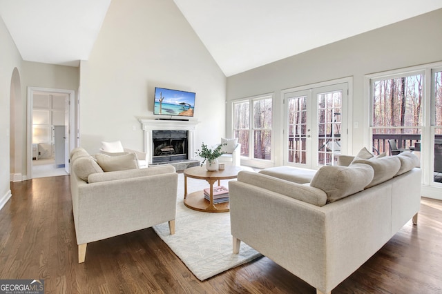 living room featuring arched walkways, a fireplace, high vaulted ceiling, and a wealth of natural light