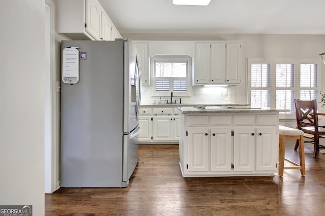 kitchen with white cabinets, a sink, freestanding refrigerator, a center island, and dark wood-style flooring