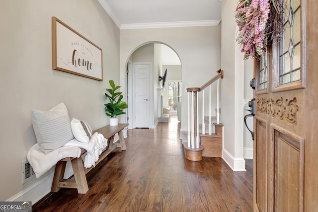 entrance foyer with dark wood-style floors, visible vents, ornamental molding, arched walkways, and stairs