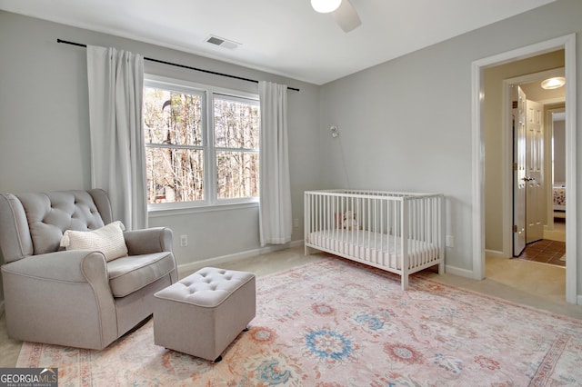 bedroom featuring a crib, baseboards, visible vents, and carpet flooring