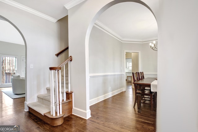 interior space with arched walkways, crown molding, wood finished floors, and baseboards