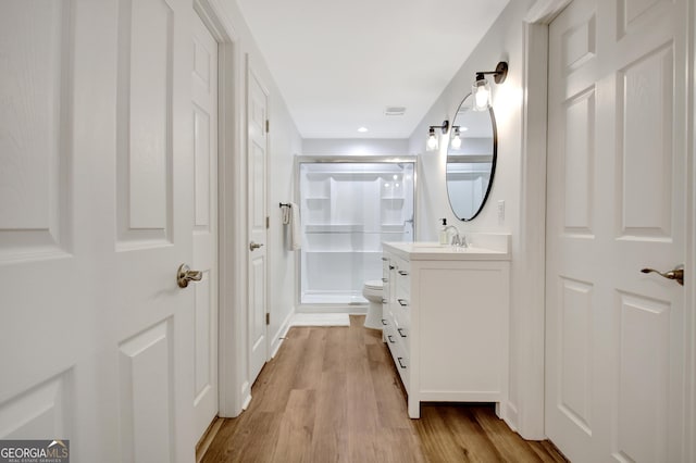 full bath featuring toilet, wood finished floors, vanity, and a stall shower