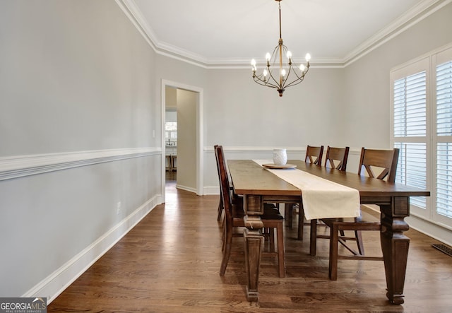 dining area featuring dark wood finished floors, an inviting chandelier, ornamental molding, and baseboards