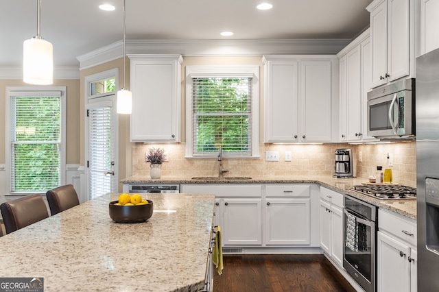 kitchen with stainless steel appliances, sink, pendant lighting, and white cabinets