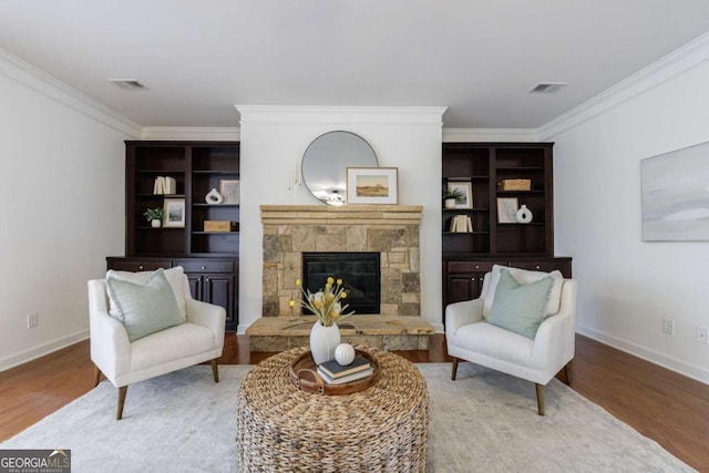 living area with crown molding, a fireplace, and hardwood / wood-style floors