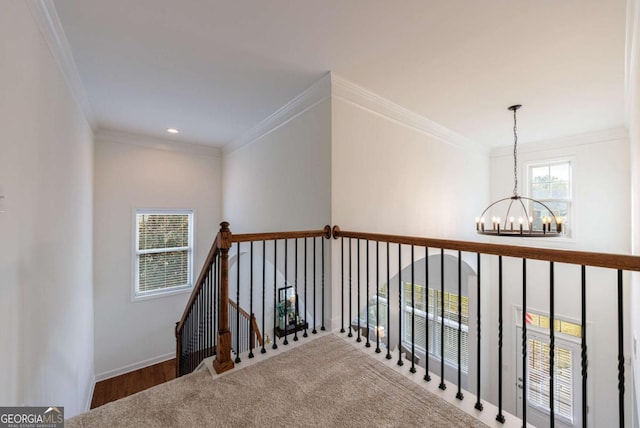 stairs with ornamental molding, a healthy amount of sunlight, and a chandelier