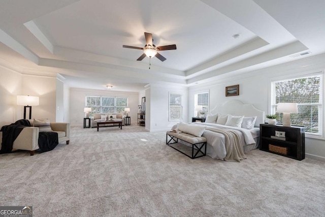 bedroom with light carpet and a tray ceiling