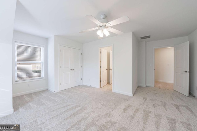 unfurnished bedroom with ceiling fan, light colored carpet, and a closet