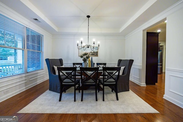 dining area featuring dark hardwood / wood-style floors, ornamental molding, a tray ceiling, and a chandelier