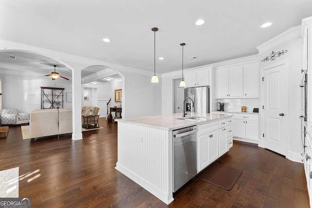 kitchen featuring appliances with stainless steel finishes, hanging light fixtures, a center island with sink, and white cabinets