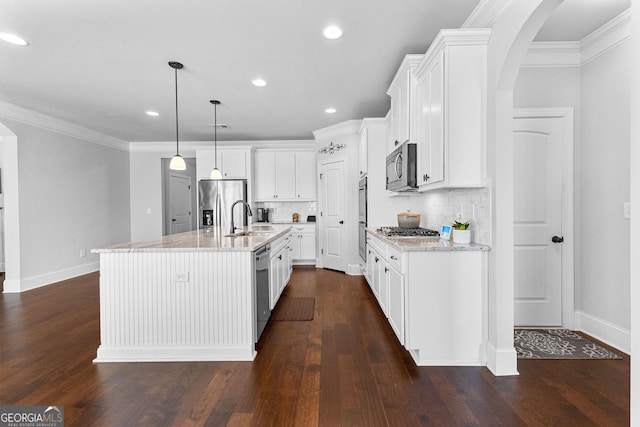 kitchen with appliances with stainless steel finishes, white cabinetry, sink, hanging light fixtures, and a kitchen island with sink