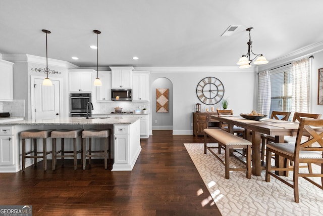 kitchen with light stone counters, hanging light fixtures, white cabinets, and appliances with stainless steel finishes