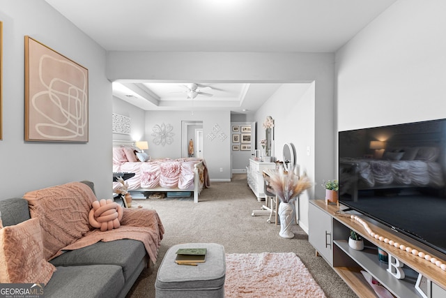 bedroom with a raised ceiling, carpet floors, and ceiling fan