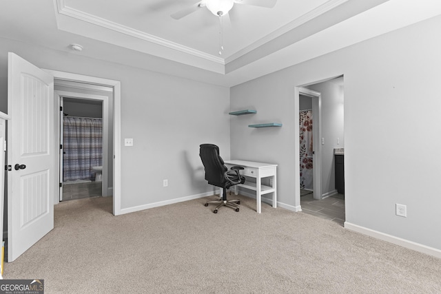 carpeted office space with crown molding, ceiling fan, and a raised ceiling