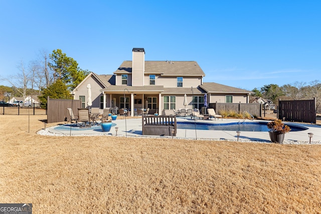 back of property featuring a fenced in pool, a yard, and a patio