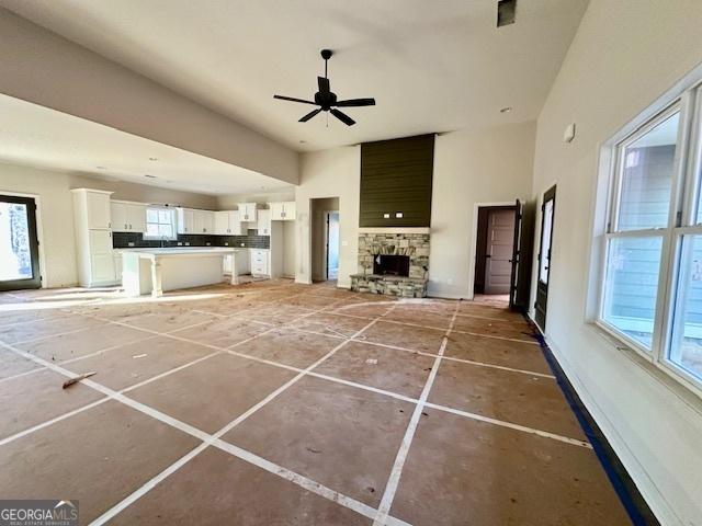 unfurnished living room with ceiling fan and a fireplace