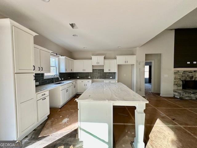 kitchen with white cabinetry, sink, a kitchen island, and backsplash