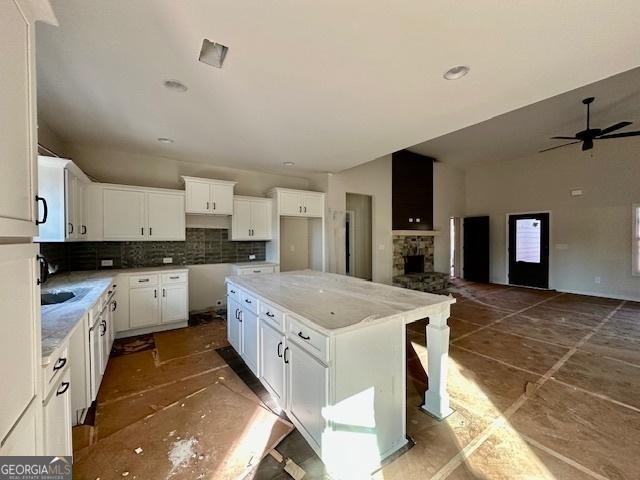 kitchen featuring white cabinetry, a kitchen island, a fireplace, and decorative backsplash