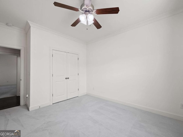 unfurnished bedroom with crown molding, light colored carpet, ceiling fan, and a closet