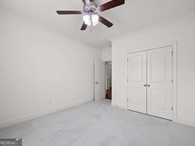 unfurnished bedroom with ceiling fan, light colored carpet, ornamental molding, and a closet