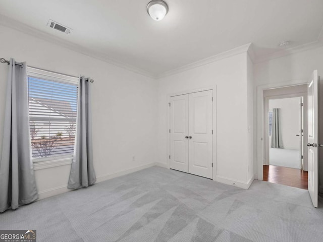 unfurnished bedroom with crown molding, light colored carpet, and a closet