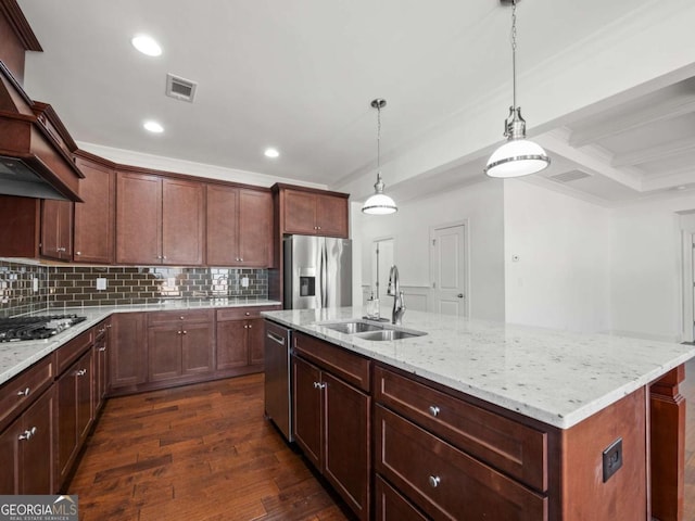 kitchen with sink, an island with sink, pendant lighting, stainless steel appliances, and decorative backsplash