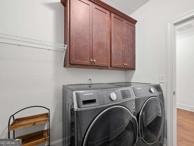 laundry area with cabinets, separate washer and dryer, and hardwood / wood-style floors