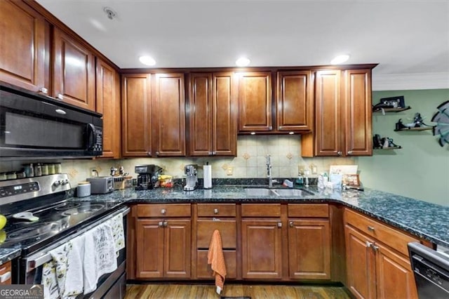 kitchen with sink, light hardwood / wood-style flooring, dark stone counters, and black appliances