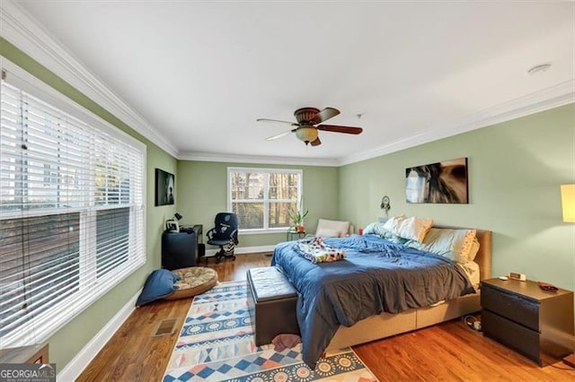 bedroom featuring hardwood / wood-style flooring, ceiling fan, and crown molding