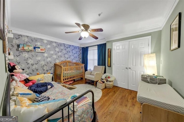 bedroom with a closet, ornamental molding, light hardwood / wood-style floors, and ceiling fan