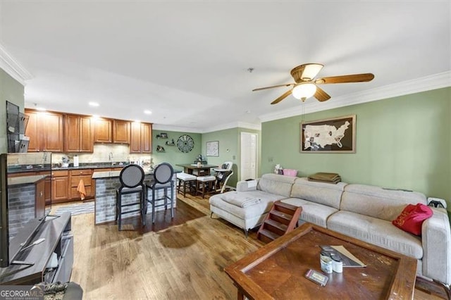 living room with ornamental molding, hardwood / wood-style floors, and ceiling fan