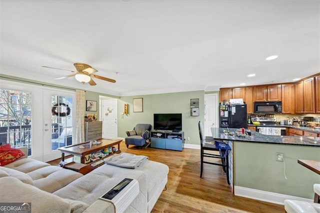 living room with french doors, ceiling fan, ornamental molding, and light wood-type flooring