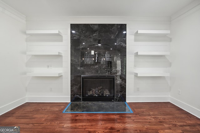 room details featuring baseboards, a tiled fireplace, and wood finished floors