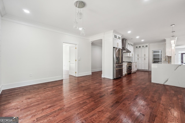 unfurnished living room with baseboards, dark wood-style flooring, crown molding, a sink, and recessed lighting