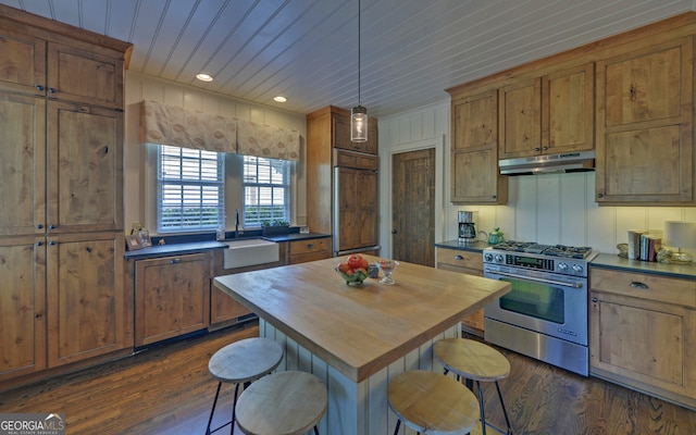 kitchen with sink, wood ceiling, stainless steel gas range, a breakfast bar, and dark hardwood / wood-style floors