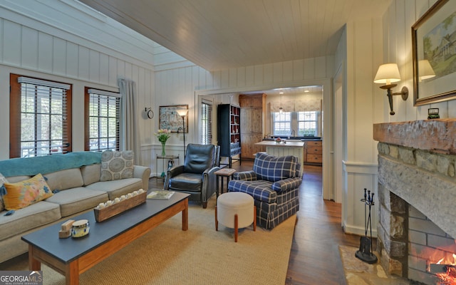 living room featuring wood ceiling, hardwood / wood-style floors, and a stone fireplace