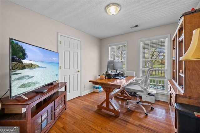 office with light hardwood / wood-style floors and a textured ceiling