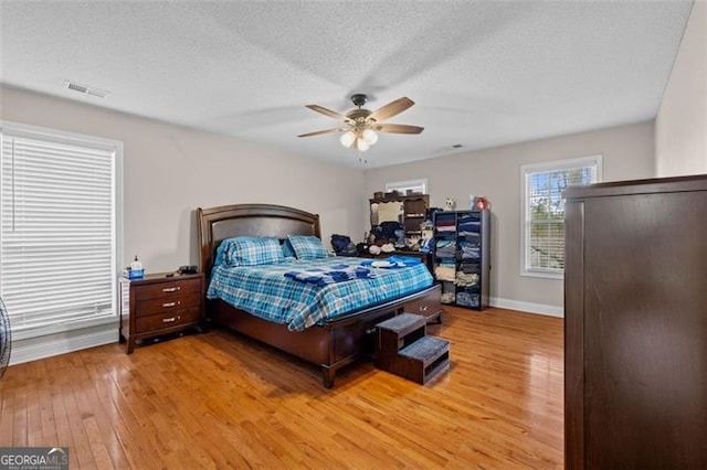 bedroom with wood-type flooring, ceiling fan, and a textured ceiling