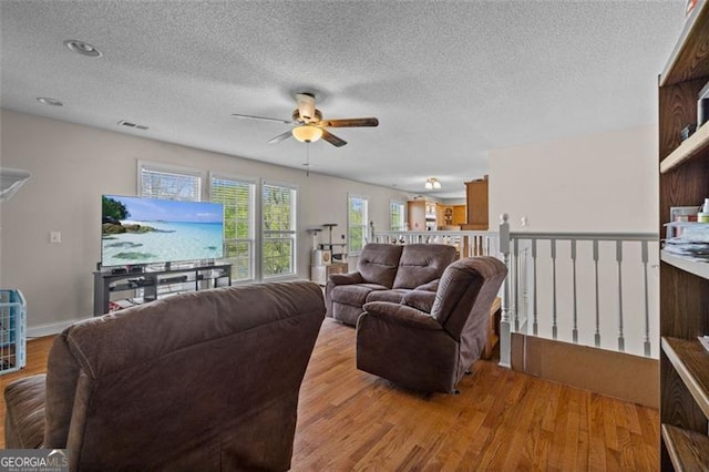 living room featuring ceiling fan, a textured ceiling, and light hardwood / wood-style flooring