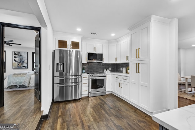 kitchen with stainless steel appliances, light stone countertops, white cabinets, and decorative backsplash