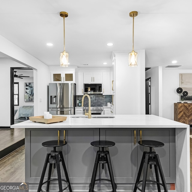 kitchen featuring stainless steel appliances, hanging light fixtures, a breakfast bar area, and white cabinets