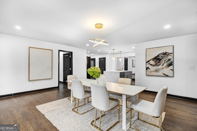 dining area with sink, a notable chandelier, and dark wood-type flooring