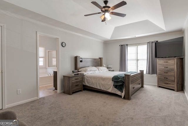 carpeted bedroom with crown molding, connected bathroom, ceiling fan, and a tray ceiling