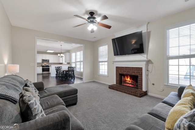 living room with carpet floors, ceiling fan with notable chandelier, and a fireplace